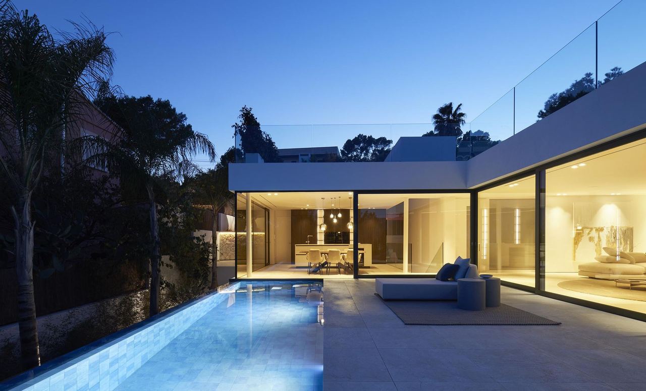 Piscina y salón iluminados al anochecer
